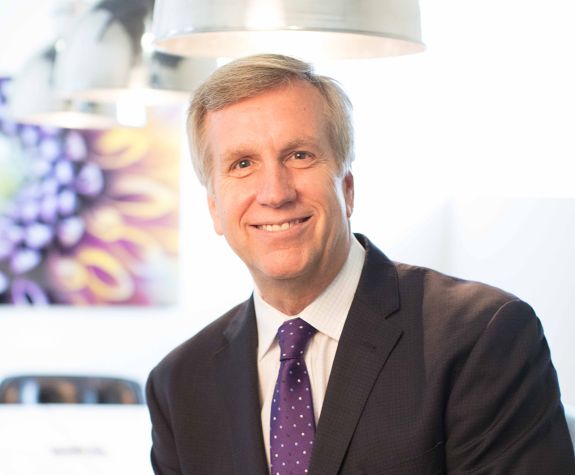 A man wearing a suit smiles for a photo indoors